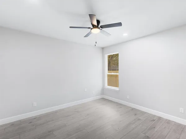 an empty room with a window and ceiling fan