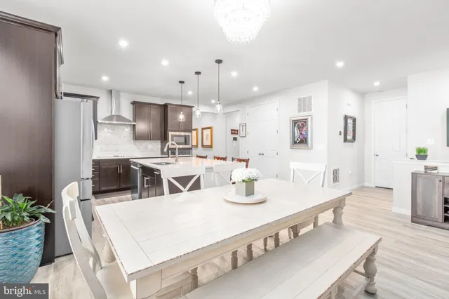 a large kitchen with stainless steel appliances kitchen island granite countertop a dining table chairs and a refrigerator