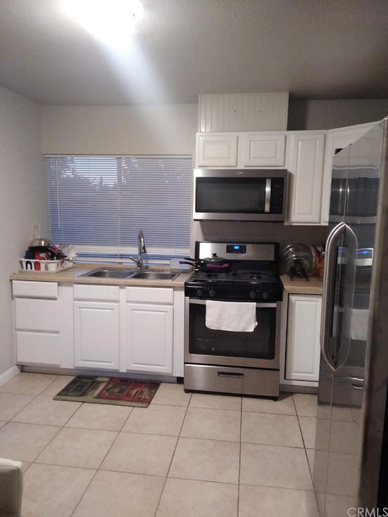 42901 Alexo Drive Lancaster, CA 93536 - Photo 16 of 20 a white kitchen with granite countertop a stove top oven microwave and cabinets