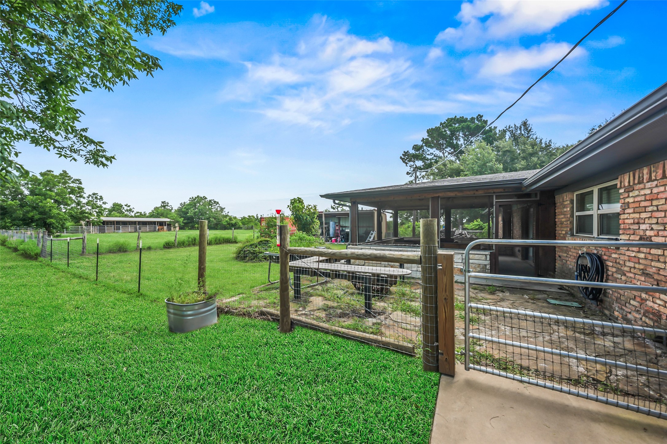 34366 Owens Road Hempstead, TX 77445 - Photo 26 of 46 Fenced backyard with a gated access ramp leading to the covered patio, providing convenient outdoor access and plenty of space to enjoy the surrounding yard.