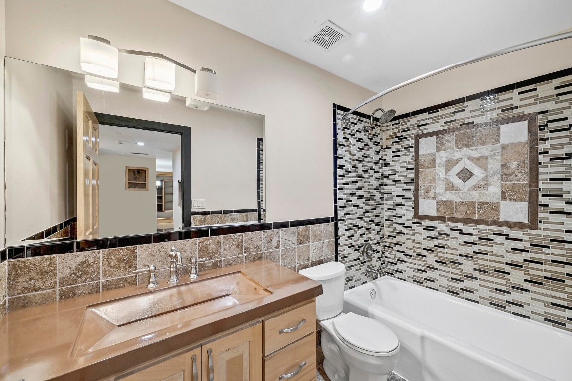 2204 Spring Creek Drive Austin, TX 78704 - Photo 15 of 34 a bathroom with a granite countertop sink toilet a mirror a vanity and shower