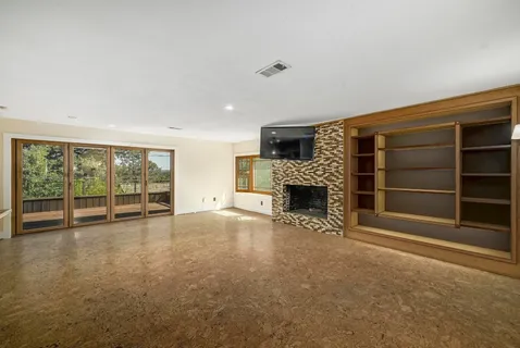 a view of an empty room with a fireplace and a window