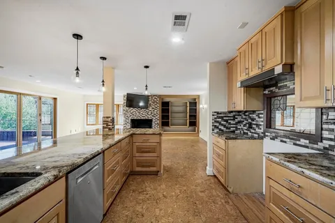 a kitchen with stainless steel appliances granite countertop a stove a sink and a refrigerator