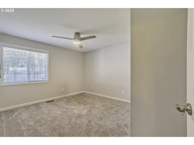 a view of an empty room with a ceiling fan and a window