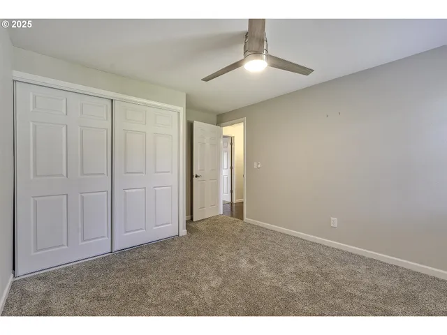 a view of an empty room and chandelier fan