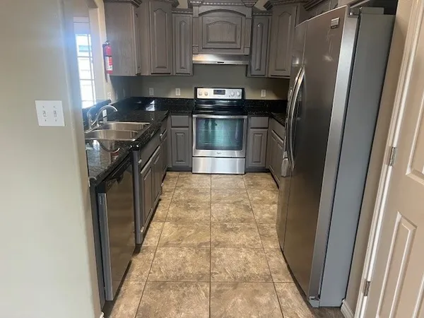 a kitchen with stainless steel appliances granite countertop a stove a refrigerator and a sink