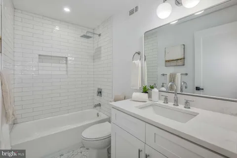 a bathroom with a granite countertop sink a toilet and bathtub