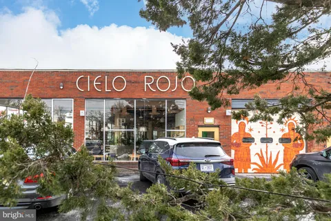 a front view of a multi story building with yard and car parked