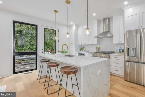 a kitchen with kitchen island a stove a refrigerator a sink and white cabinets with wooden floor