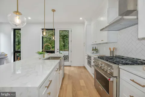 a kitchen with stainless steel appliances granite countertop a stove a sink and a wooden floors