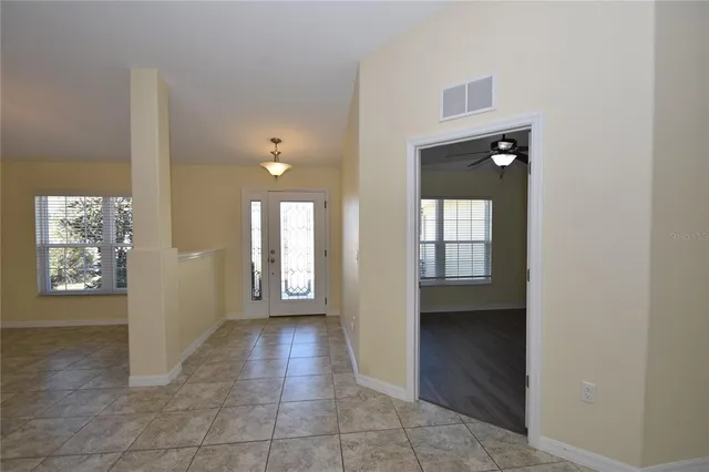 an empty room with wooden floor ceiling fan and windows