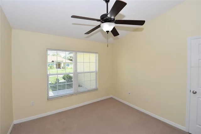 an empty room with a window and a fan