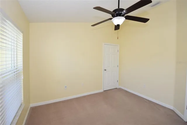 an empty room with a window and a fan