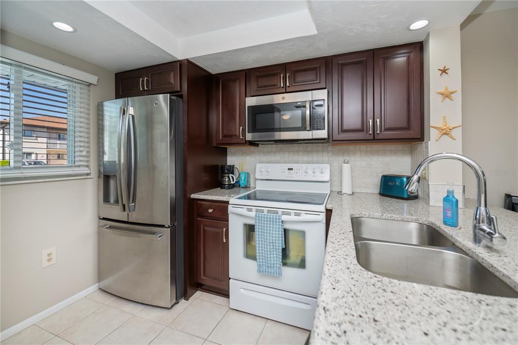 25275 Rampart Boulevard, Unit 1802 Punta Gorda, FL 33983 - Photo 11 of 41 a kitchen with stainless steel appliances granite countertop a refrigerator a stove a sink and a microwave