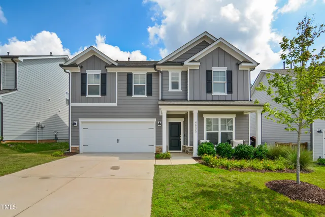 a view of a white house with a small yard and large tree