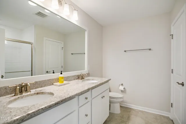 a bathroom with a granite countertop sink a toilet and a mirror