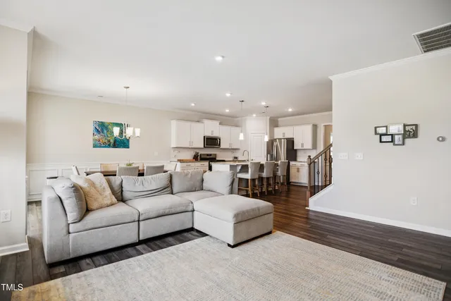 a living room with furniture and kitchen view with wooden floor