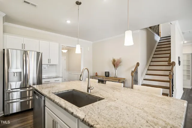 a kitchen with granite countertop a refrigerator a sink and wooden floor