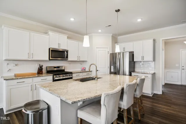a kitchen with stainless steel appliances granite countertop a kitchen island hardwood floor and a sink