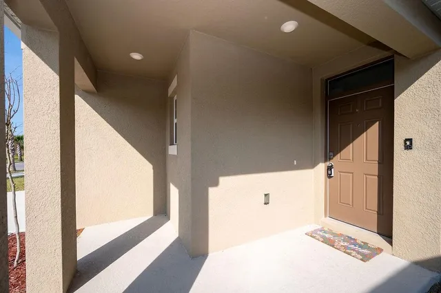 a view of a hallway to a bedroom with wooden floor and windows