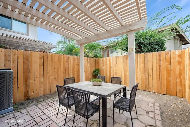 a patio with table and chairs and potted plants