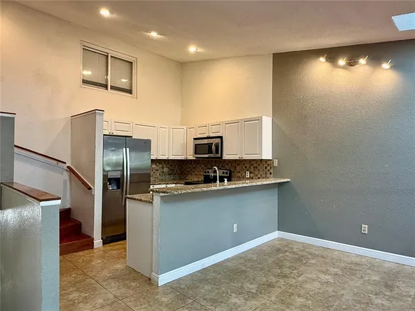 a kitchen with stainless steel appliances granite countertop a sink and a refrigerator