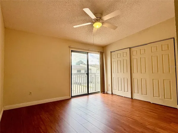 an empty room with wooden floor and ceiling fan