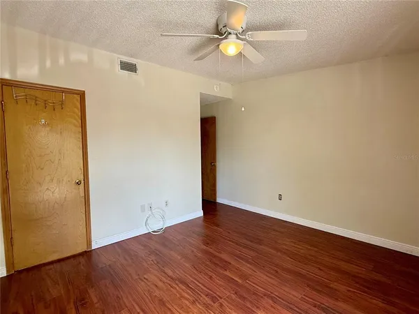 an empty room with wooden floor and a ceiling fan