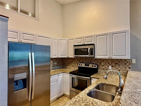 a kitchen with stainless steel appliances granite countertop a sink refrigerator and microwave