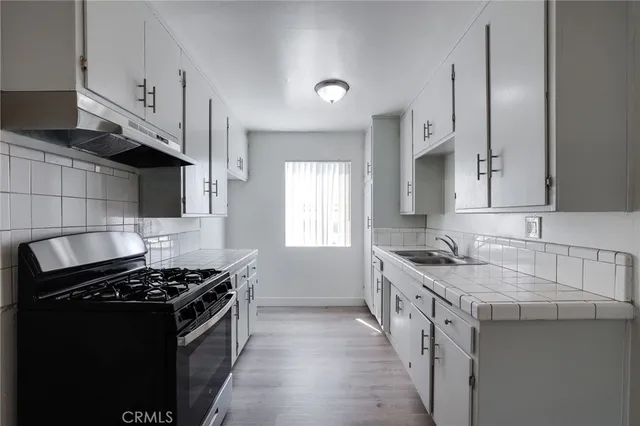 a kitchen with a sink stove top oven and cabinets