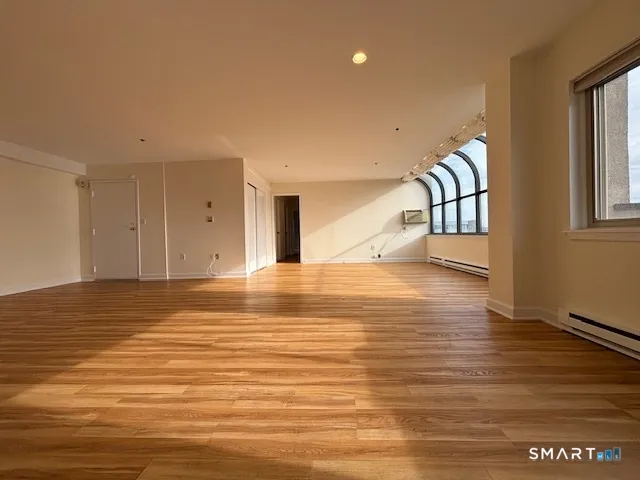 a view of an empty room with window and wooden floor