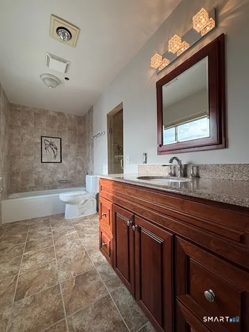 a spacious bathroom with a granite countertop sink a toilet mirror and bathtub