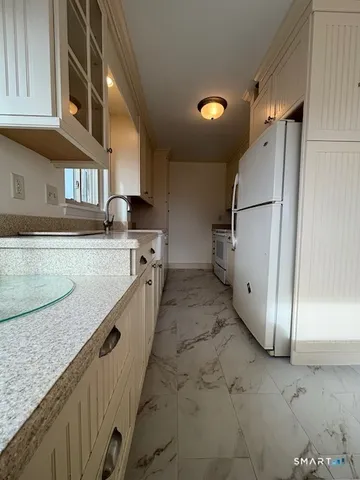 a kitchen with granite countertop a sink a refrigerator and a stove