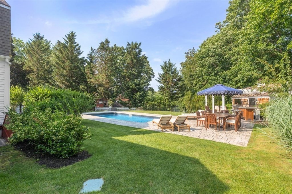 241 Jerusalem Road Cohasset, MA 02025 - Photo 6 of 42 a view of a swimming pool with a table and chairs under an umbrella