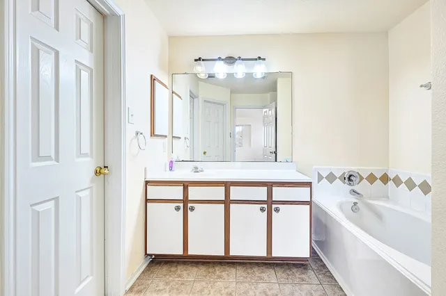 a bathroom with a sink a bathtub a mirror a vanity and bathtub