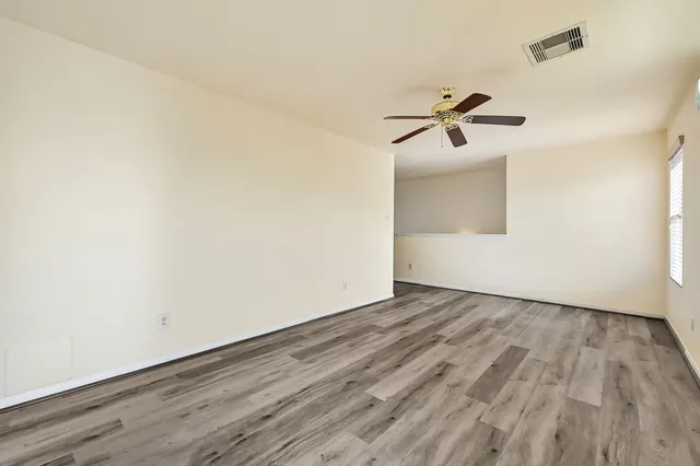 an empty room with wooden floor and fan