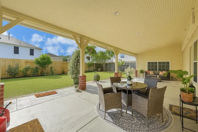 a view of a patio with couches table and chairs under an umbrella