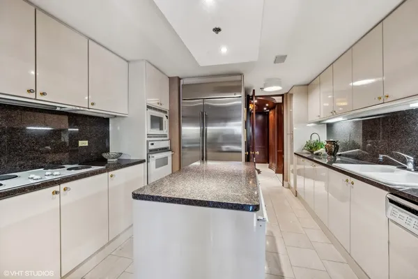 a large kitchen with granite countertop a sink stainless steel appliances and white cabinets