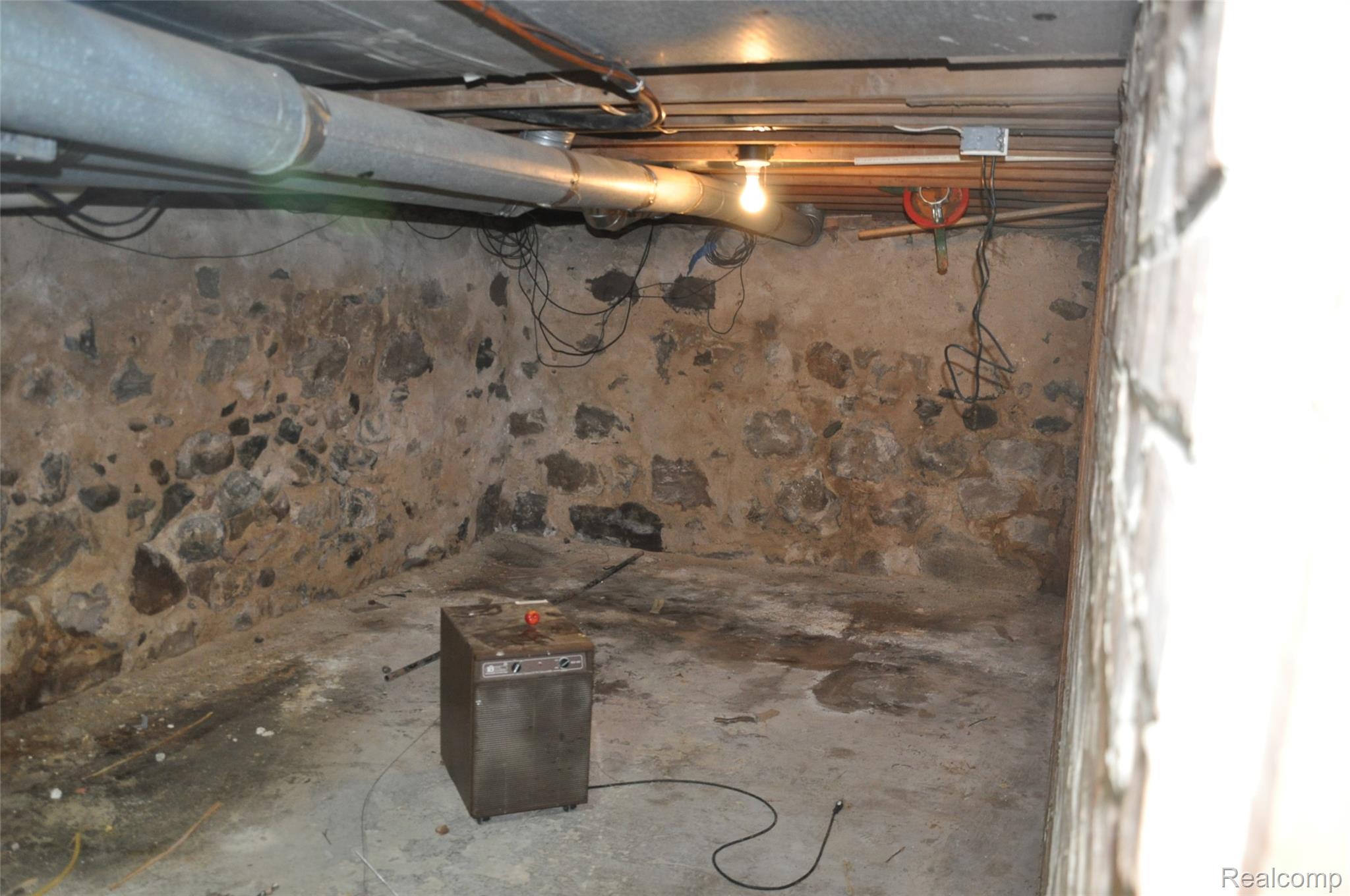 3954 Mayville Road Silverwood, MI 48760 - Photo 28 of 30 Unfinished basement space featuring stone and mortar walls, concrete flooring, exposed ceiling joists, and visible utility pipes