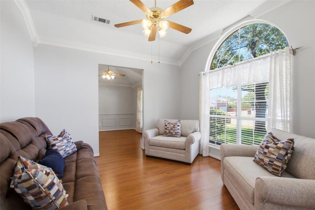 4218 Glistening Spring Rowlett, TX 75088 - Photo 4 of 39 Vaulted ceiling living area featuring wood-finish flooring, a large arched window with horizontal blinds, a ceiling fan, and crown molding