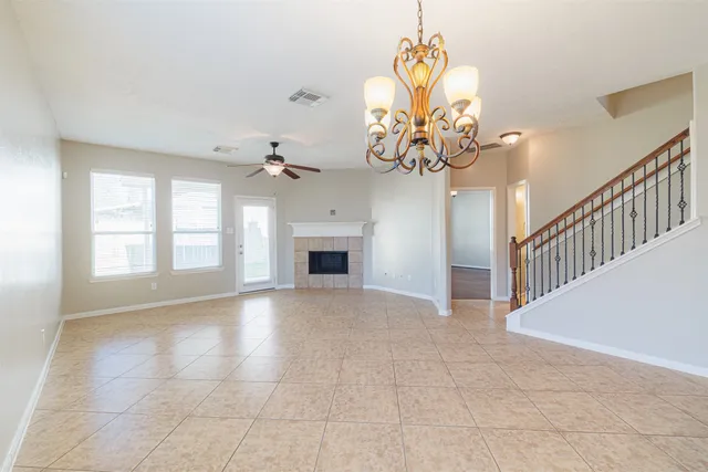 a view of an empty room with a chandelier fan