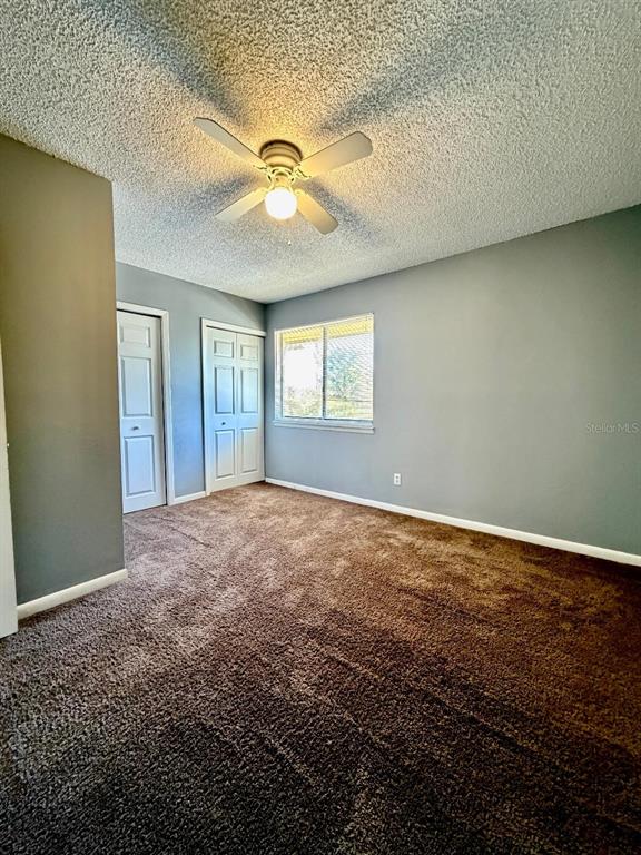 22726 Gage Loop, Unit 43 Land O' Lakes, FL 34639 - Photo 18 of 24 an empty room with a chandelier fan and windows