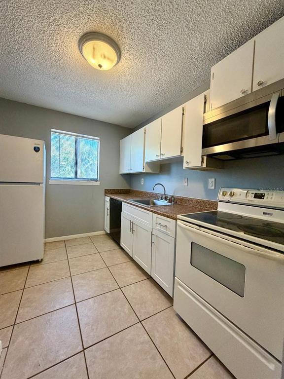 22726 Gage Loop, Unit 43 Land O' Lakes, FL 34639 - Photo 4 of 24 a kitchen with stainless steel appliances granite countertop a stove a sink and a microwave
