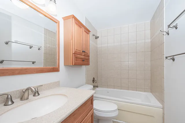 a bathroom with a granite countertop bathtub shower sink vanity mirror and toilet