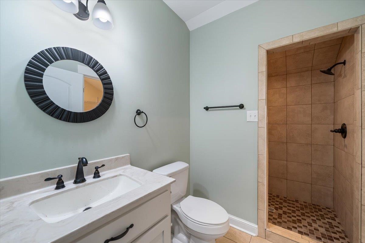 206 Deen Road Brighton, TN 38011 - Photo 27 of 35 Bathroom featuring a tiled walk-in shower with a patterned floor, a single vanity with a solid surface countertop, and matte black fixtures.