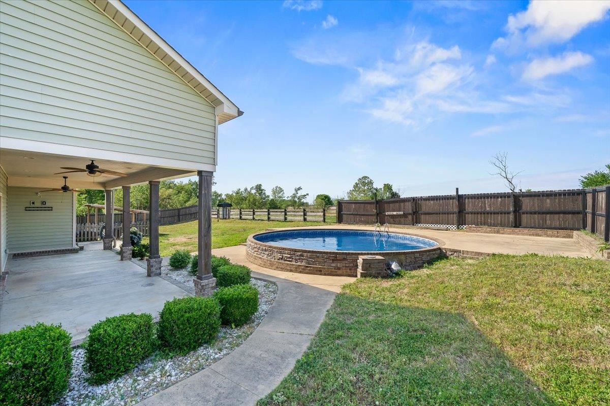 206 Deen Road Brighton, TN 38011 - Photo 28 of 35 Expansive outdoor living area featuring a covered patio with ceiling fans, a concrete walkway, and a round, stone-clad swimming pool