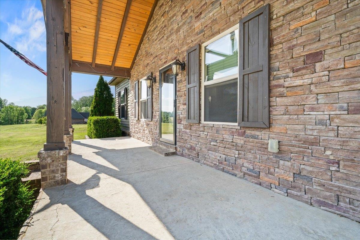 206 Deen Road Brighton, TN 38011 - Photo 7 of 35 Spacious covered porch with a natural stone facade, wood-plank ceiling, and sturdy structural columns