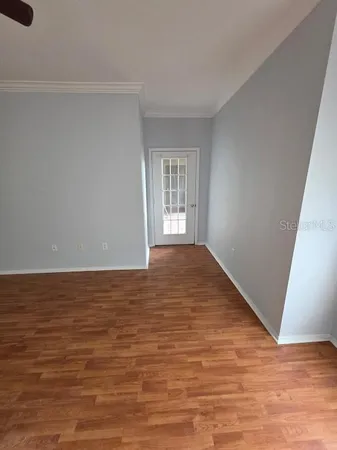 a view of an empty room with wooden floor and stairs