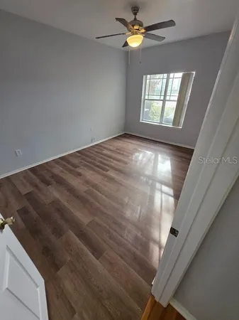 a view of an empty room with wooden floor and a window