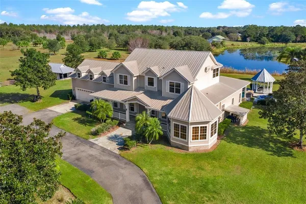 an aerial view of a house with swimming pool and lake view